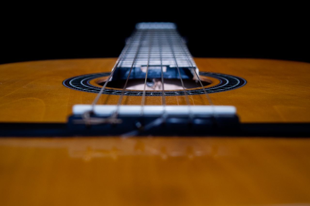Home Detailed close-up shot of the strings on a classical acoustic guitar, focusing on the soundhole.